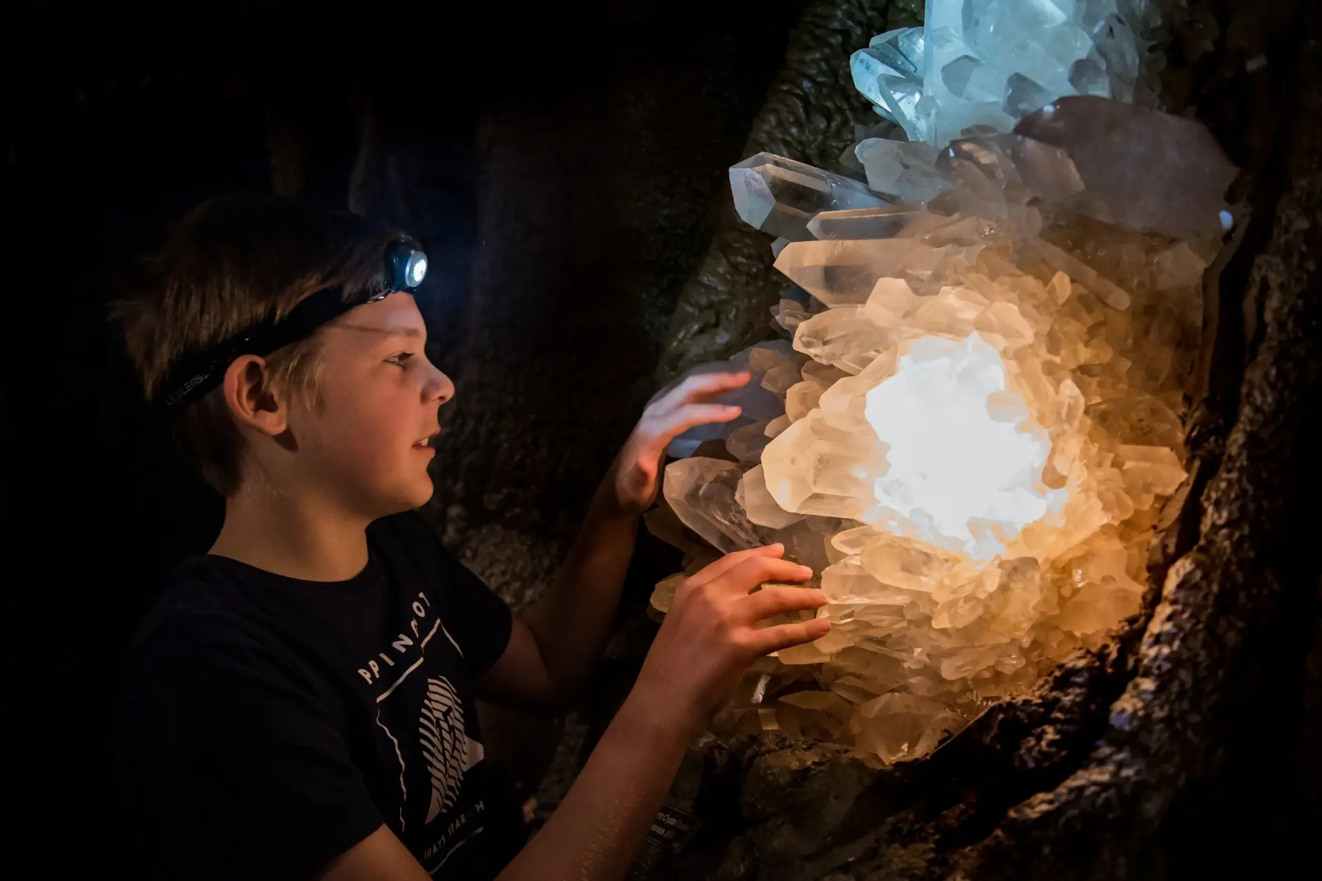 Child touching a glowing crystal formation inside the caves